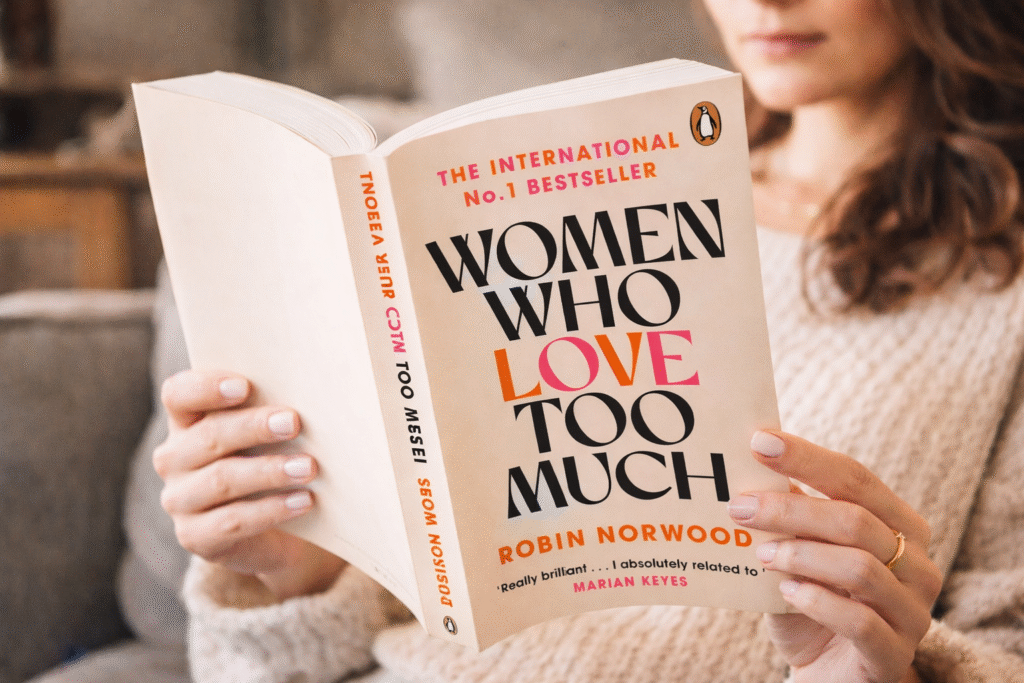 Woman reading Women Who Love Too Much, symbolizing repeated relationship patterns and emotional dependency